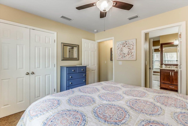 carpeted bedroom featuring ceiling fan, ensuite bathroom, and a closet