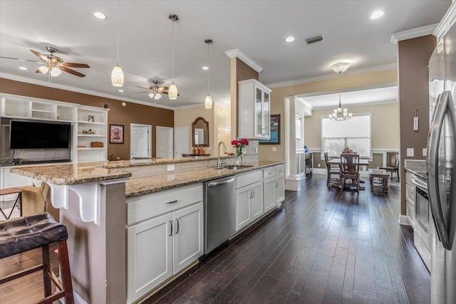 kitchen featuring stainless steel appliances, white cabinetry, hanging light fixtures, and a kitchen breakfast bar