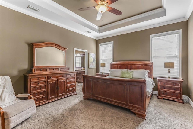 bedroom with light colored carpet, connected bathroom, a tray ceiling, and ceiling fan