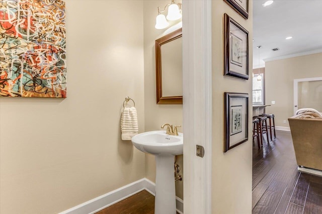 bathroom featuring crown molding, hardwood / wood-style flooring, and sink