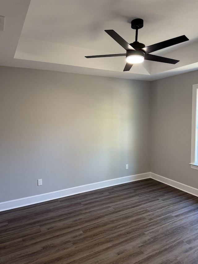 spare room featuring ceiling fan, dark hardwood / wood-style flooring, and a raised ceiling