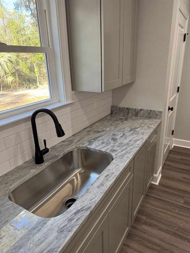 kitchen featuring tasteful backsplash, dark hardwood / wood-style floors, sink, and light stone counters