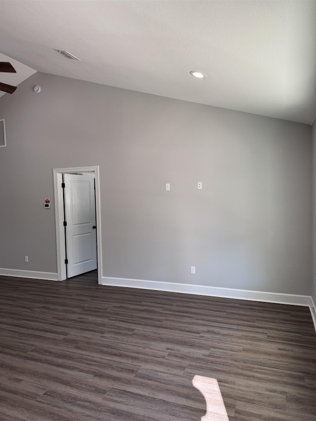 spare room with dark wood-type flooring and vaulted ceiling