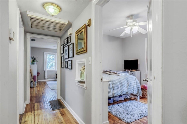 hall with visible vents, baseboards, and wood finished floors