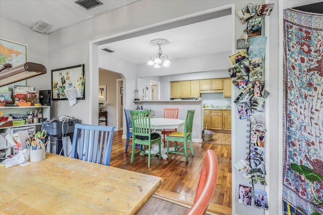 dining area featuring arched walkways, a notable chandelier, visible vents, and wood finished floors