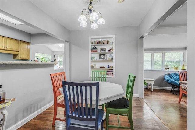 dining room featuring an inviting chandelier, baseboards, built in shelves, and wood finished floors