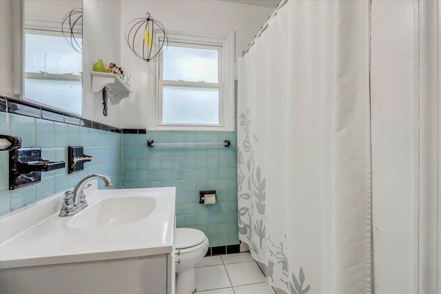 bathroom featuring wainscoting, tile patterned flooring, vanity, toilet, and tile walls