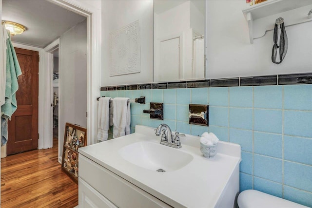 bathroom featuring vanity, wood finished floors, toilet, tile walls, and a wainscoted wall