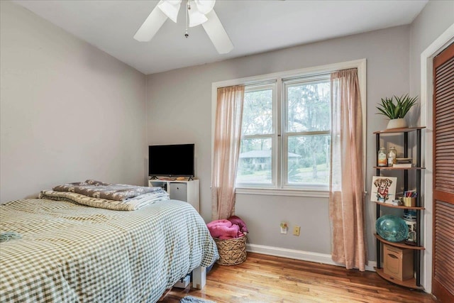 bedroom with ceiling fan, baseboards, multiple windows, and wood finished floors
