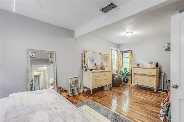 bedroom featuring beam ceiling, wood finished floors, and visible vents