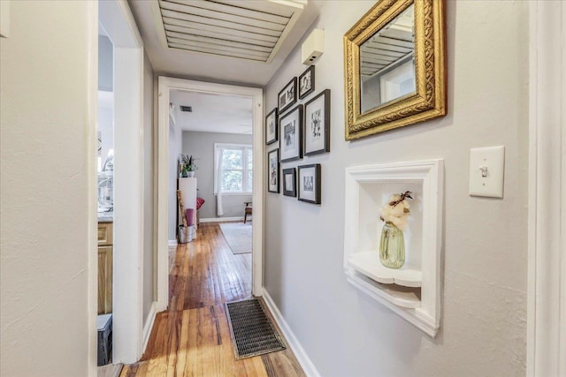 corridor with baseboards, visible vents, and wood finished floors