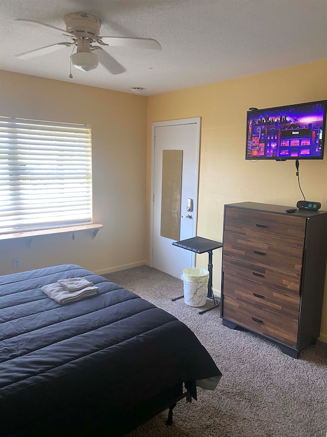 carpeted bedroom featuring ceiling fan and a textured ceiling