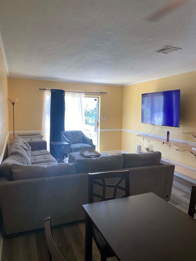 living room with wood-type flooring, a textured ceiling, and ornamental molding