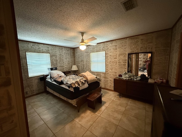 bedroom with a textured ceiling, light tile patterned floors, ceiling fan, and visible vents