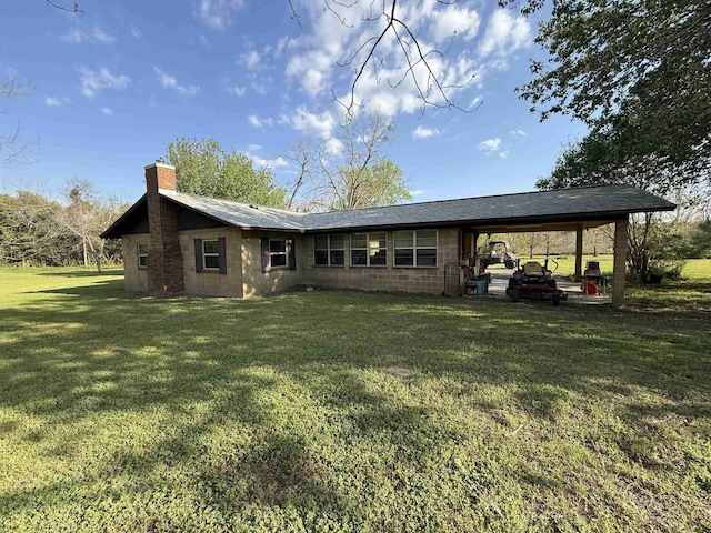 rear view of property featuring an attached carport, a yard, concrete block siding, and a chimney