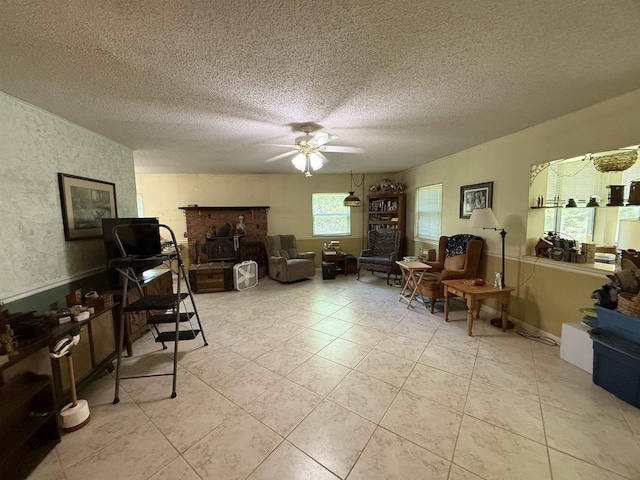 living room with ceiling fan, light tile patterned flooring, a fireplace, and a textured ceiling