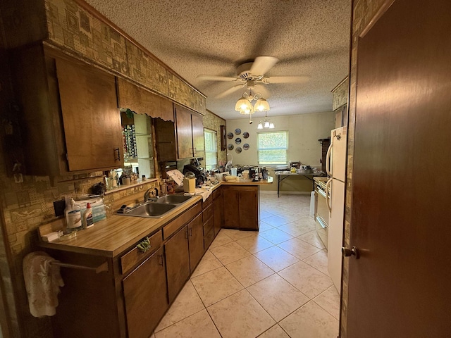 kitchen featuring a sink, ceiling fan, a peninsula, a textured ceiling, and light tile patterned flooring