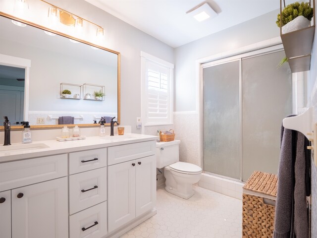 bathroom featuring walk in shower, vanity, toilet, and tile walls