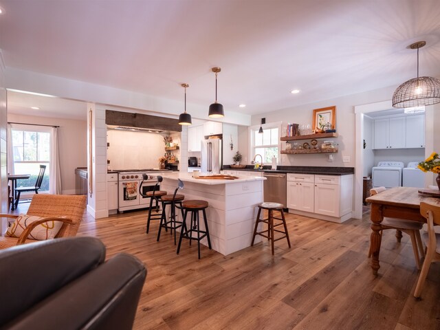 kitchen featuring light wood-type flooring, hanging light fixtures, washer and dryer, and a healthy amount of sunlight