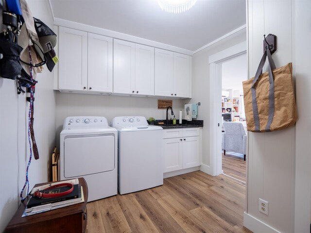 clothes washing area with cabinets, light hardwood / wood-style floors, separate washer and dryer, and sink