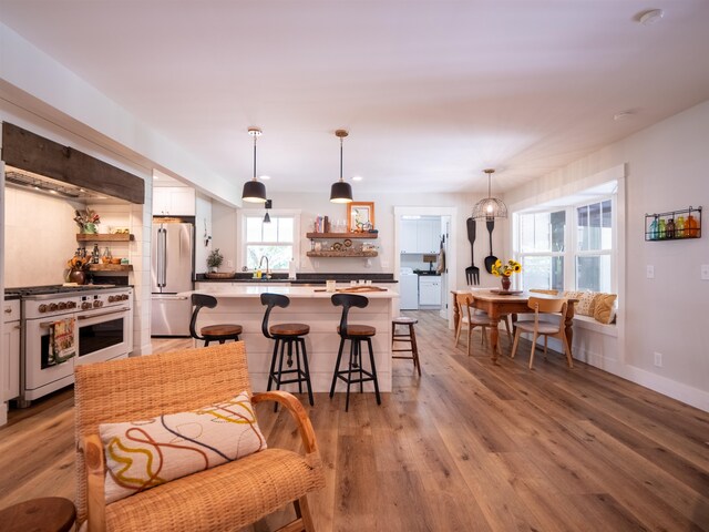 kitchen featuring white cabinets, high quality appliances, decorative light fixtures, and light wood-type flooring