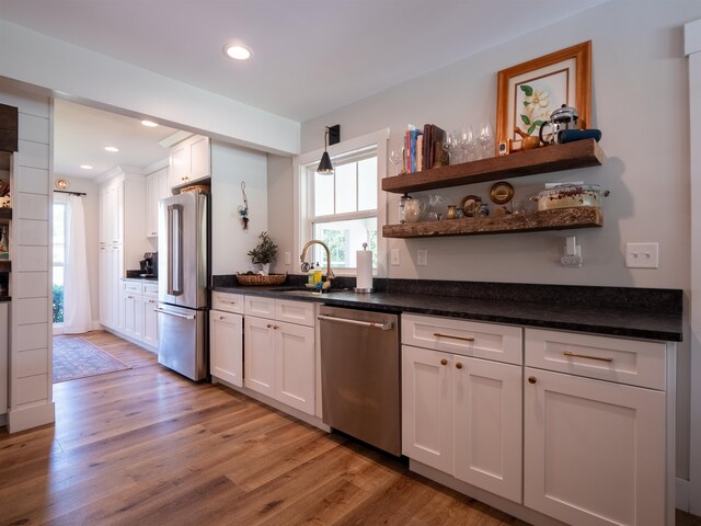 kitchen featuring white cabinets, light wood-type flooring, stainless steel appliances, and sink