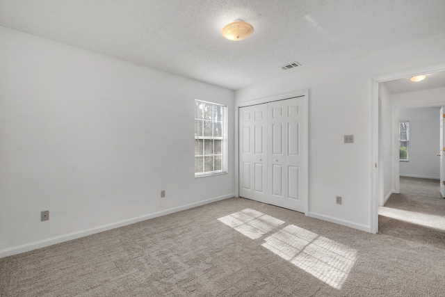 unfurnished bedroom with light colored carpet, a textured ceiling, and a closet