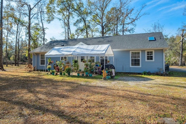 rear view of house with cooling unit and a yard