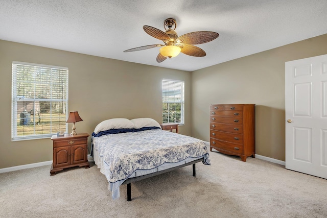 bedroom with ceiling fan, light carpet, and a textured ceiling