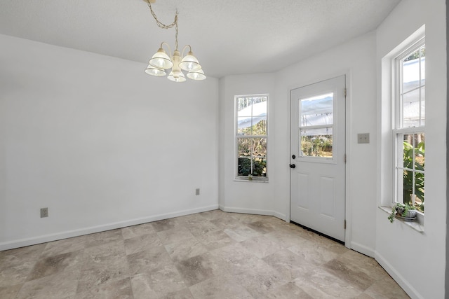 doorway with a notable chandelier and a textured ceiling