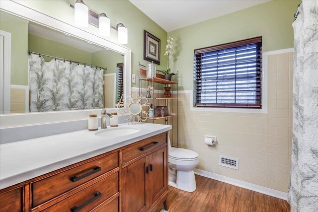 818 Watt Dr, Tallahassee, FL 32303 - bathroom with wainscoting, toilet, wood finished floors, vanity, and tile walls