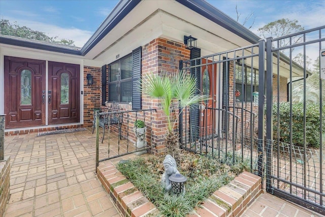 doorway to property featuring brick siding and a porch