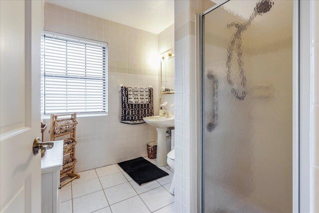 818 Watt Dr, Tallahassee, FL 32303 - bathroom with toilet, a sink, tile walls, tile patterned floors, and a stall shower