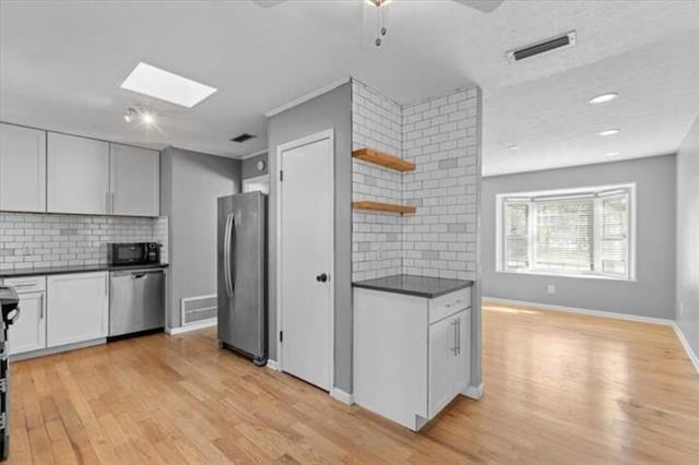 kitchen featuring appliances with stainless steel finishes, dark countertops, visible vents, and open shelves