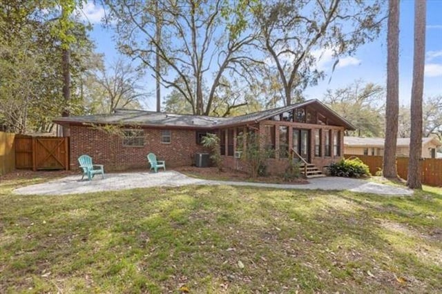 back of house with a yard, brick siding, a patio area, and a fenced backyard