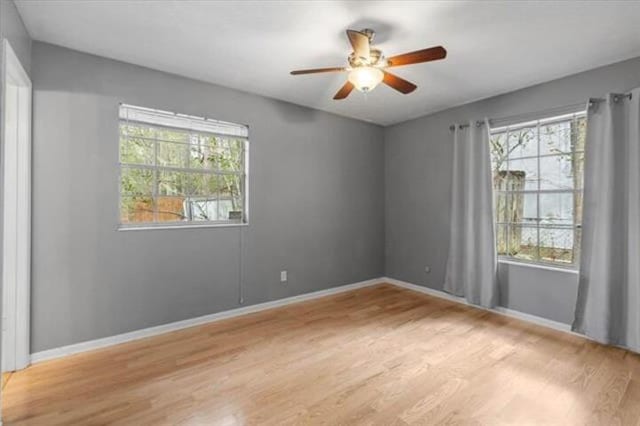 spare room featuring light wood-type flooring, baseboards, and a ceiling fan