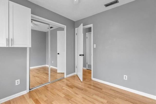 unfurnished bedroom featuring a closet, visible vents, a ceiling fan, light wood-type flooring, and baseboards