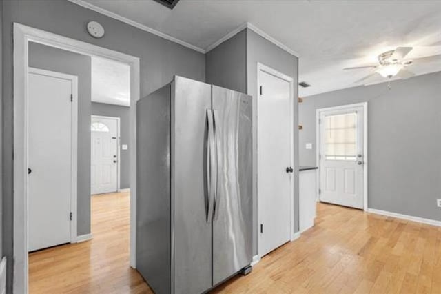 kitchen with light wood-type flooring, freestanding refrigerator, ornamental molding, and baseboards