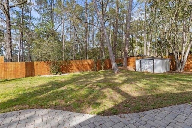 view of yard with a fenced backyard, an outdoor structure, and a shed