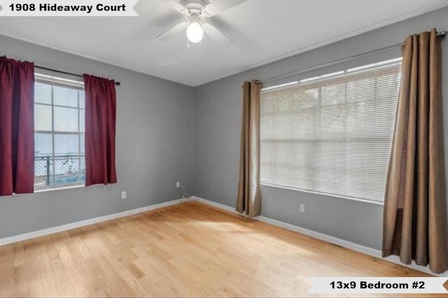 spare room featuring a ceiling fan, light wood-type flooring, and baseboards