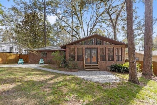 view of front of house featuring entry steps, brick siding, a patio, and fence