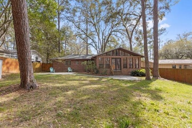 rear view of property featuring entry steps, a patio area, a lawn, and a fenced backyard