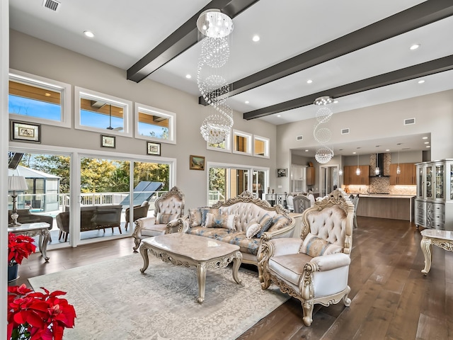 living room with a towering ceiling, beam ceiling, dark hardwood / wood-style flooring, and a notable chandelier