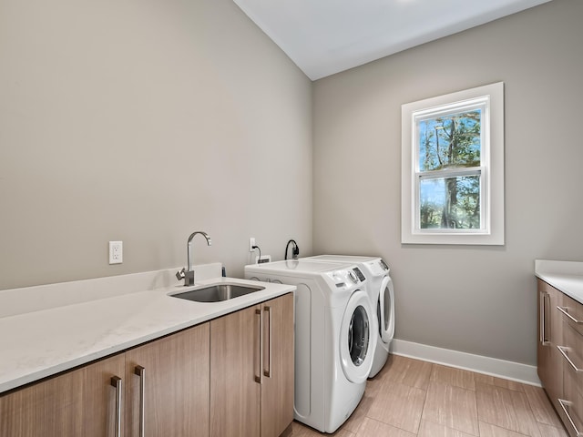 laundry room featuring washer and dryer, sink, cabinets, and light hardwood / wood-style floors