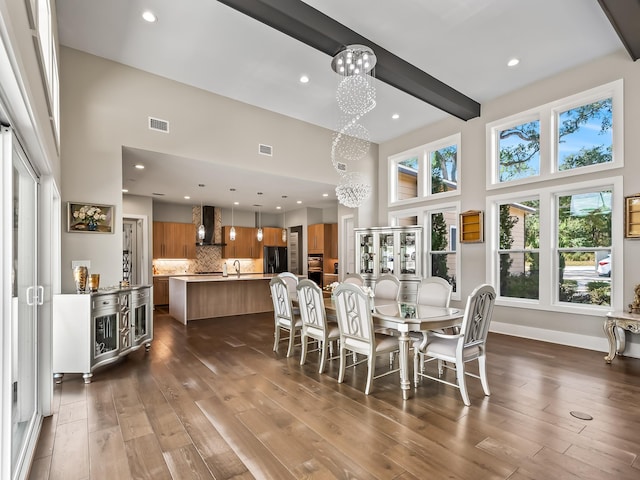 dining area featuring beamed ceiling, a towering ceiling, dark wood-type flooring, and a notable chandelier