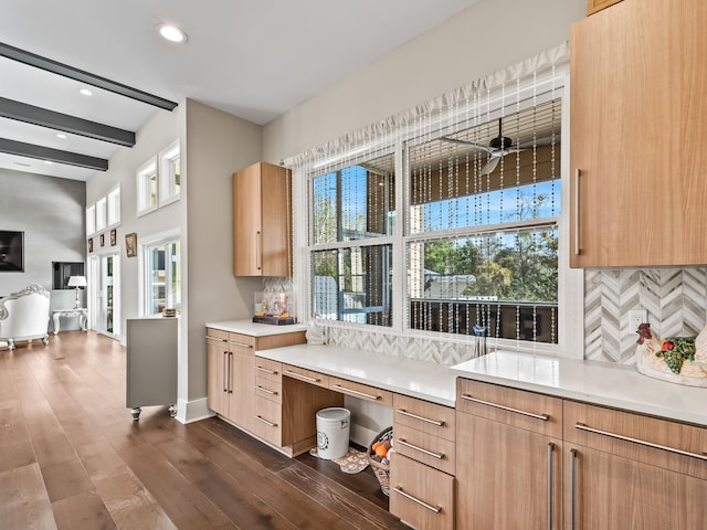 kitchen featuring ceiling fan, dark hardwood / wood-style flooring, beamed ceiling, decorative backsplash, and light brown cabinetry