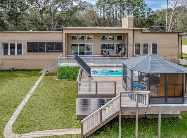 back of house featuring a lawn, a sunroom, and a hot tub