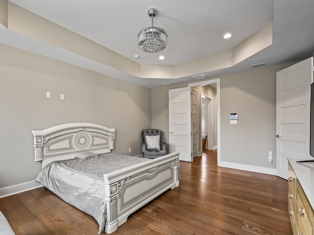 bedroom featuring a notable chandelier, dark hardwood / wood-style floors, and a raised ceiling