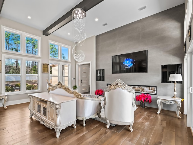 living room featuring beam ceiling, dark hardwood / wood-style floors, a notable chandelier, and a high ceiling