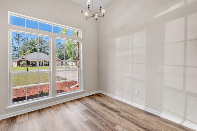 spare room with hardwood / wood-style floors and an inviting chandelier